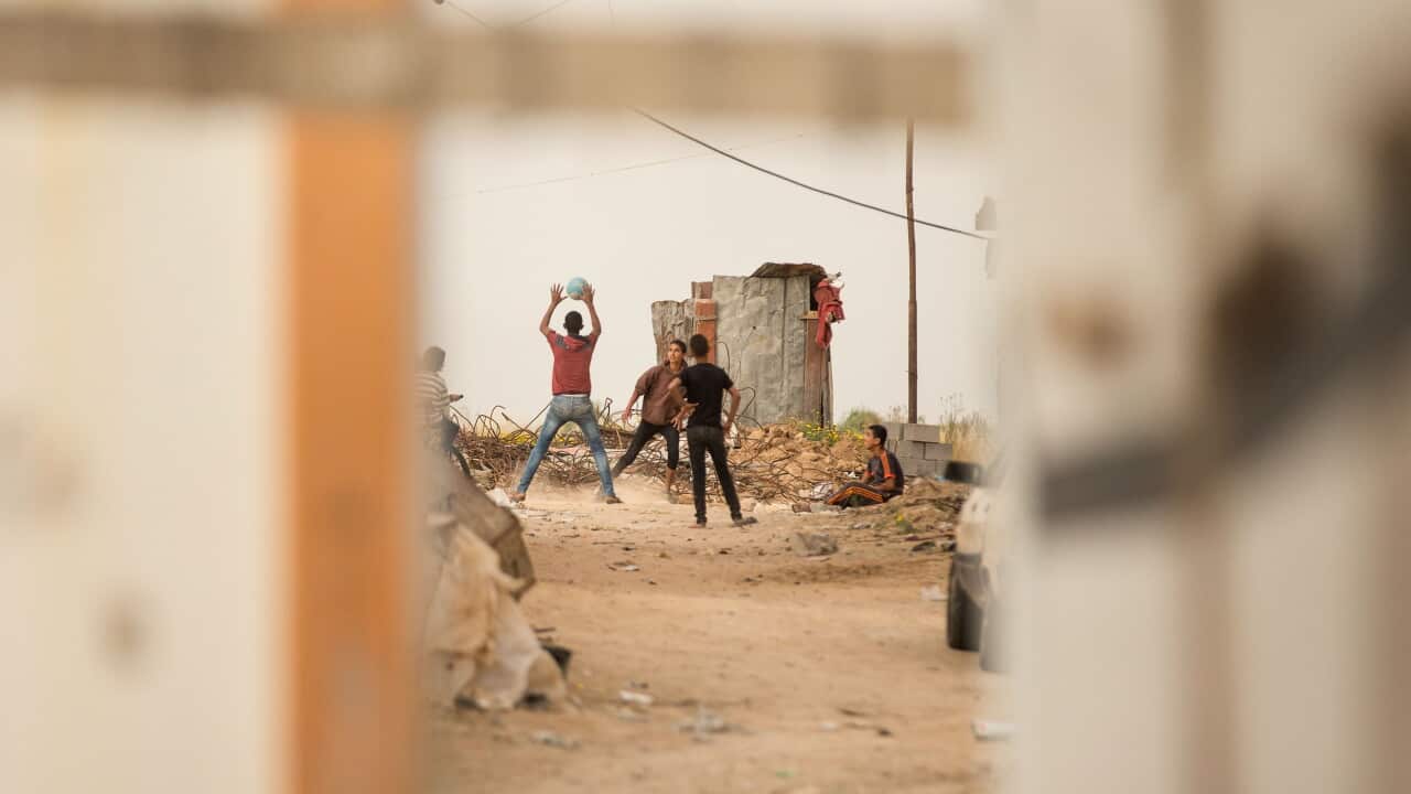 Youth play soccer amongst the ruined homes of the small village of Khuza, East Khan Yunis