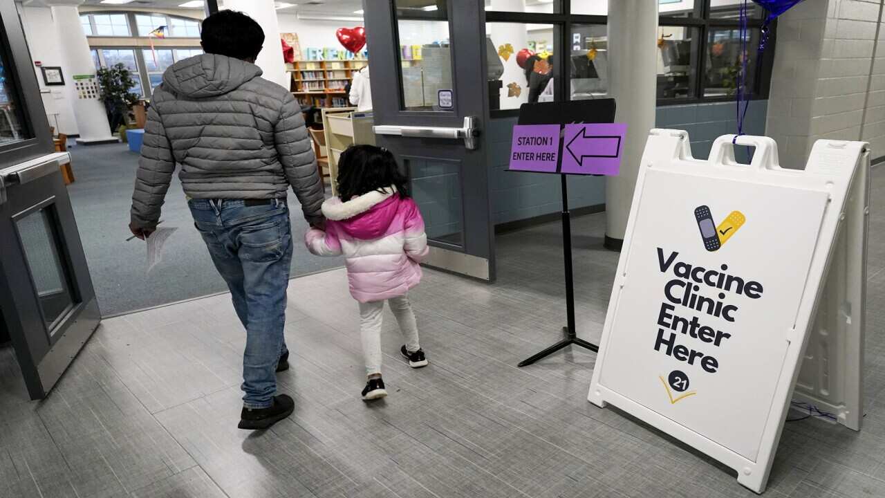 Information sign is seen as a child and her parent walk to take the Pfizer COVID-19 vaccine for children