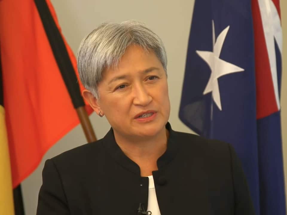 Penny Wong standing in front of Australian flag.