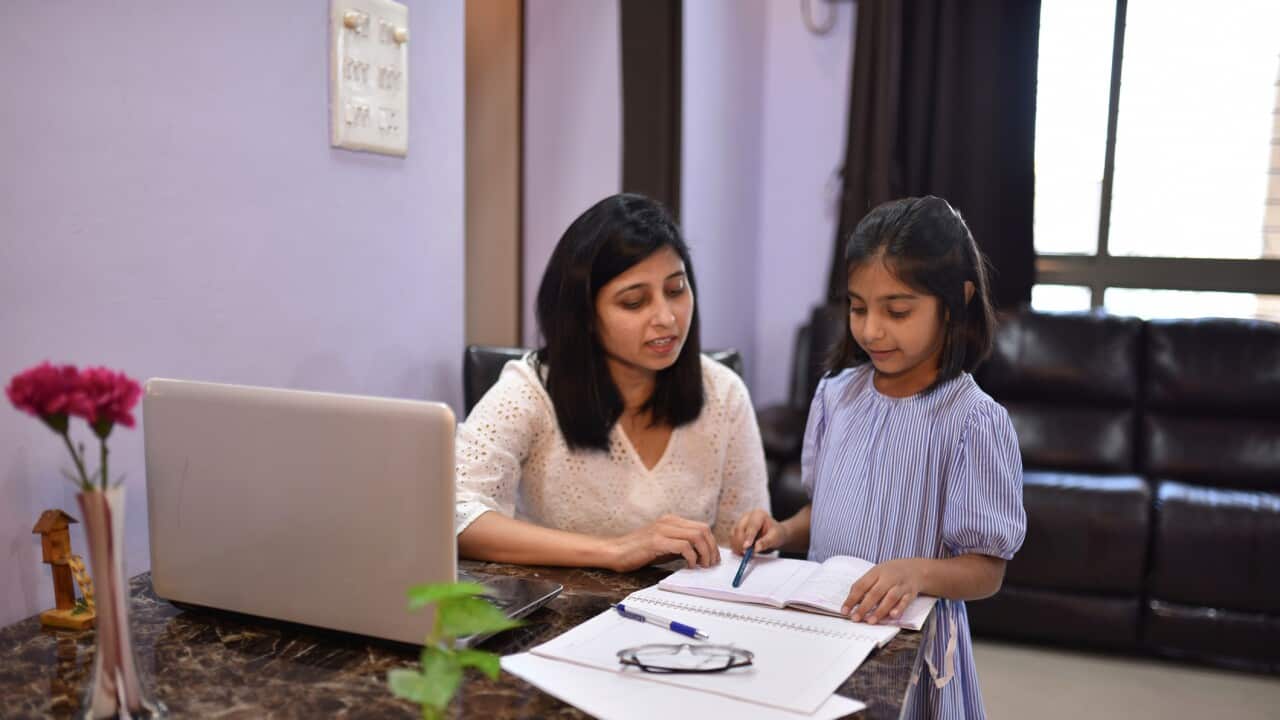 Mother working from home and helping her daughter in Homework