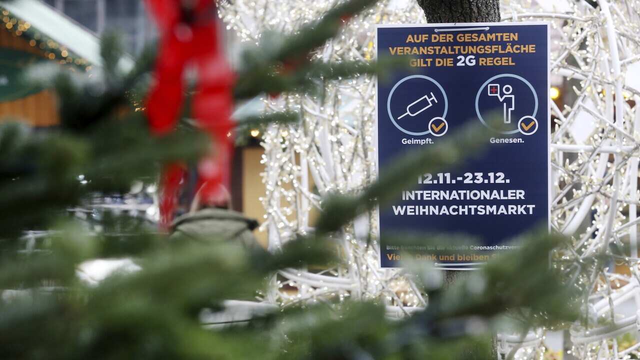 A sign indicating COVID-19 restrictions at the entrance of a Christmas market in Essen, Germany