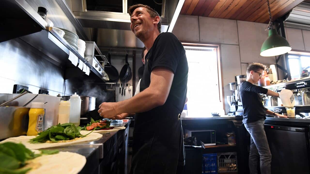 Workers at a restaurant in Brisbane prepare food and coffee for customers.