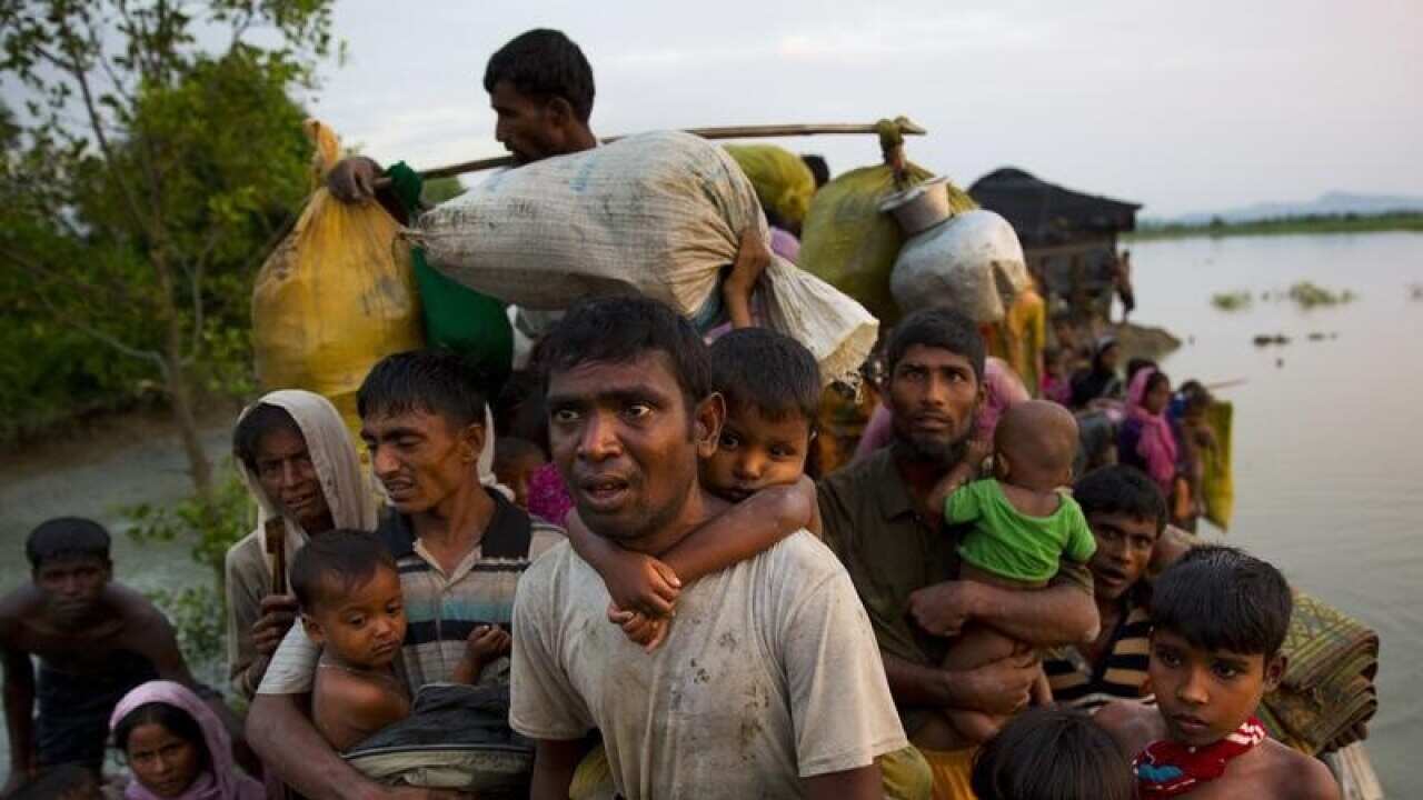 File image of Rohingya Muslims carry their young children over water.