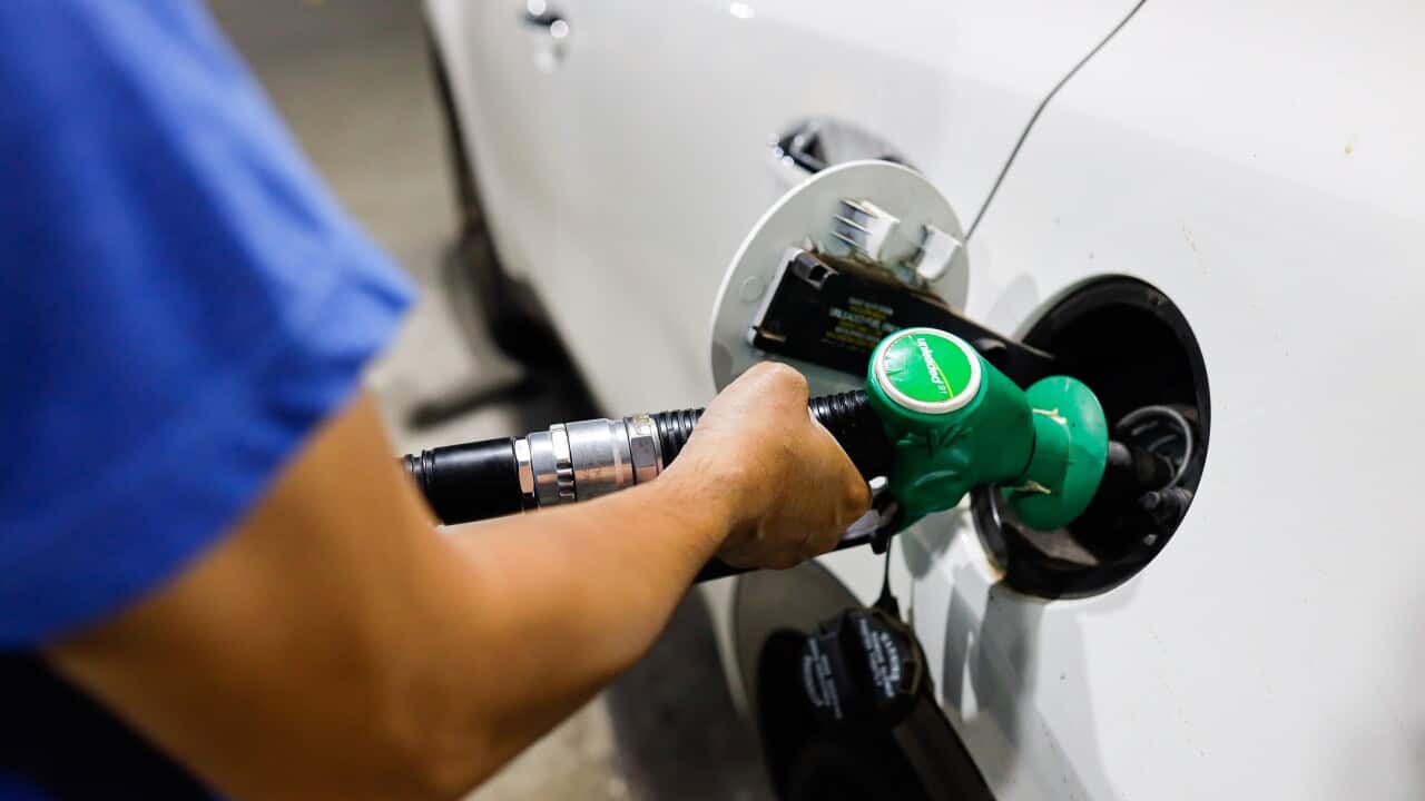A gas attendant fills their car with petrol at a petrol