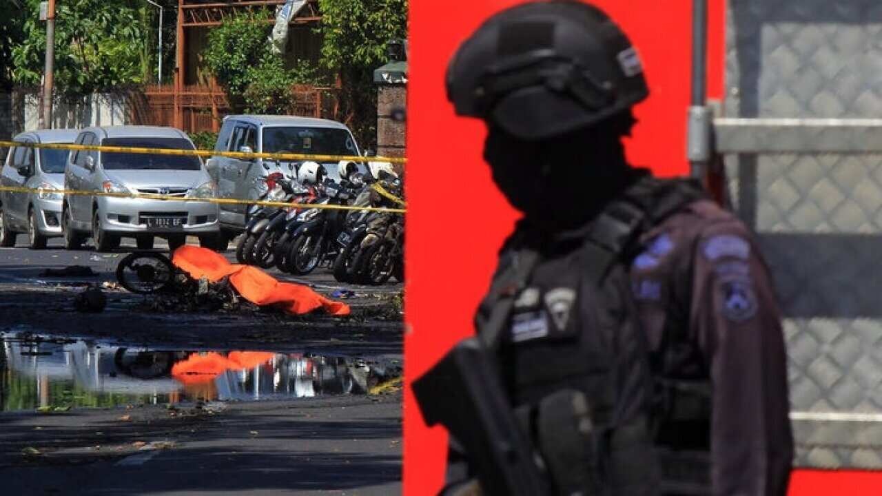 An Indonesian anti-terror policeman stands guard at the blast site in Surabaya.