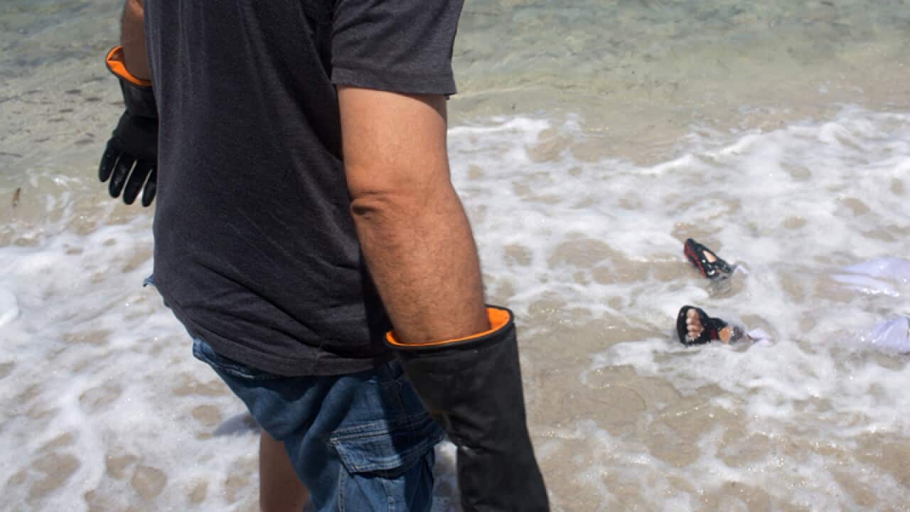 A worker for the Red Crescent prepares to pull the a body of a migrant