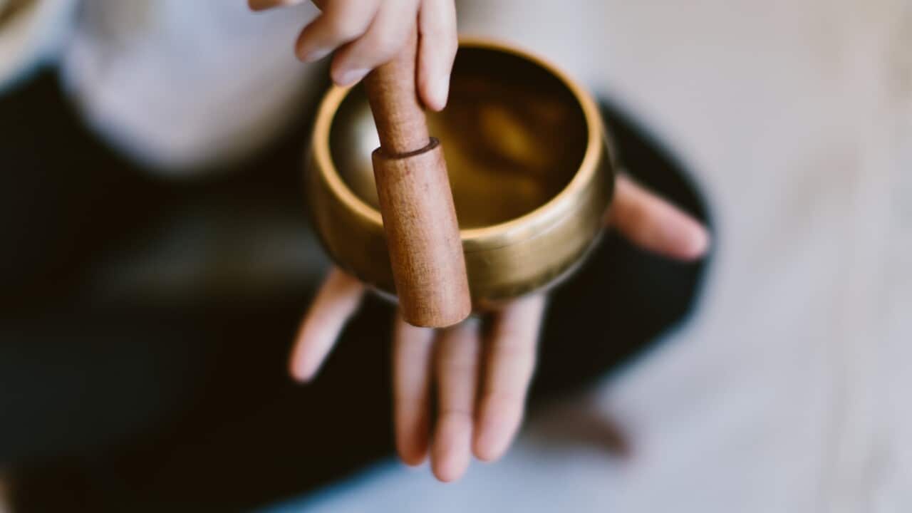 A woman using a Tibetan meditation singing bowl.
