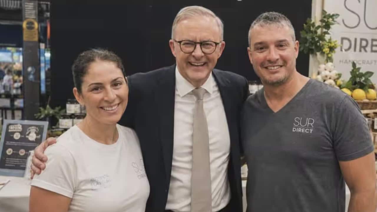 Anthony Albanese stands smiling with a man and a woman in an AI-generated image.