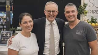 Anthony Albanese stands smiling with a man and a woman in an AI-generated image.