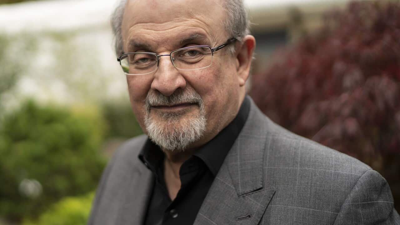 Portrait of Salman Rushdie smiling warmly in a grey blazer.