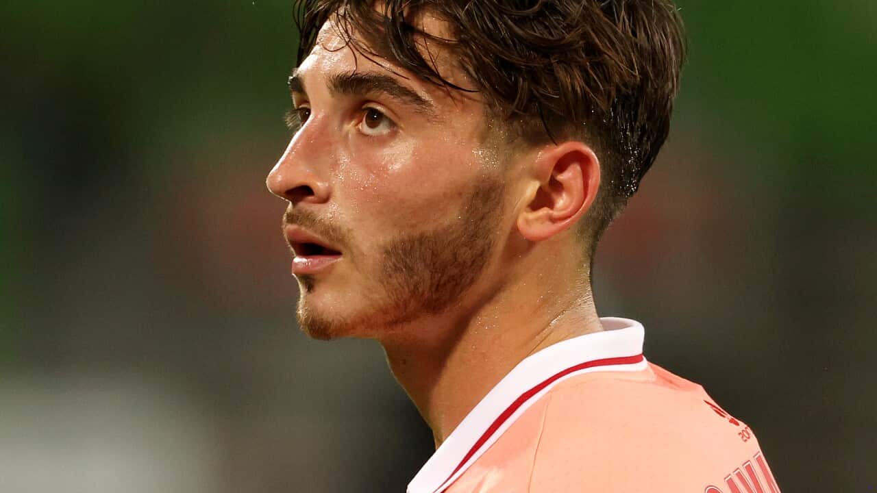 A man standing on a football field looking on.