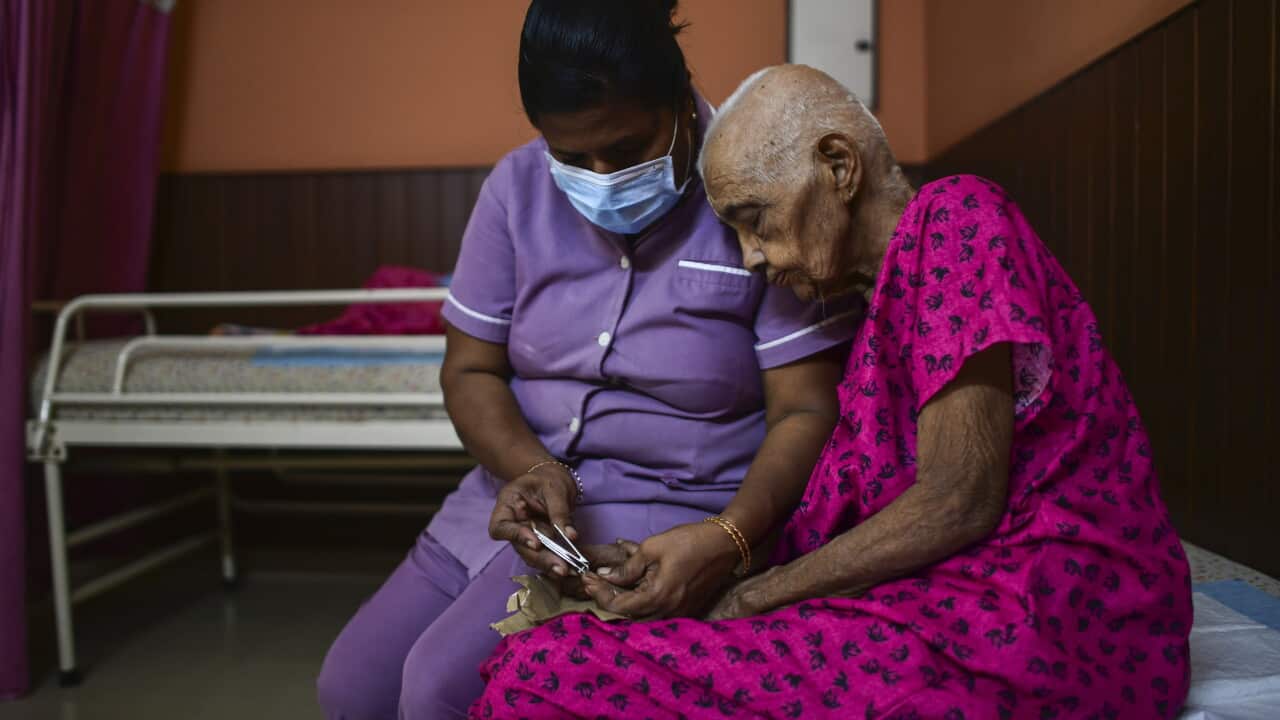 Mini, a nurse, trims the nails of an elderly woman