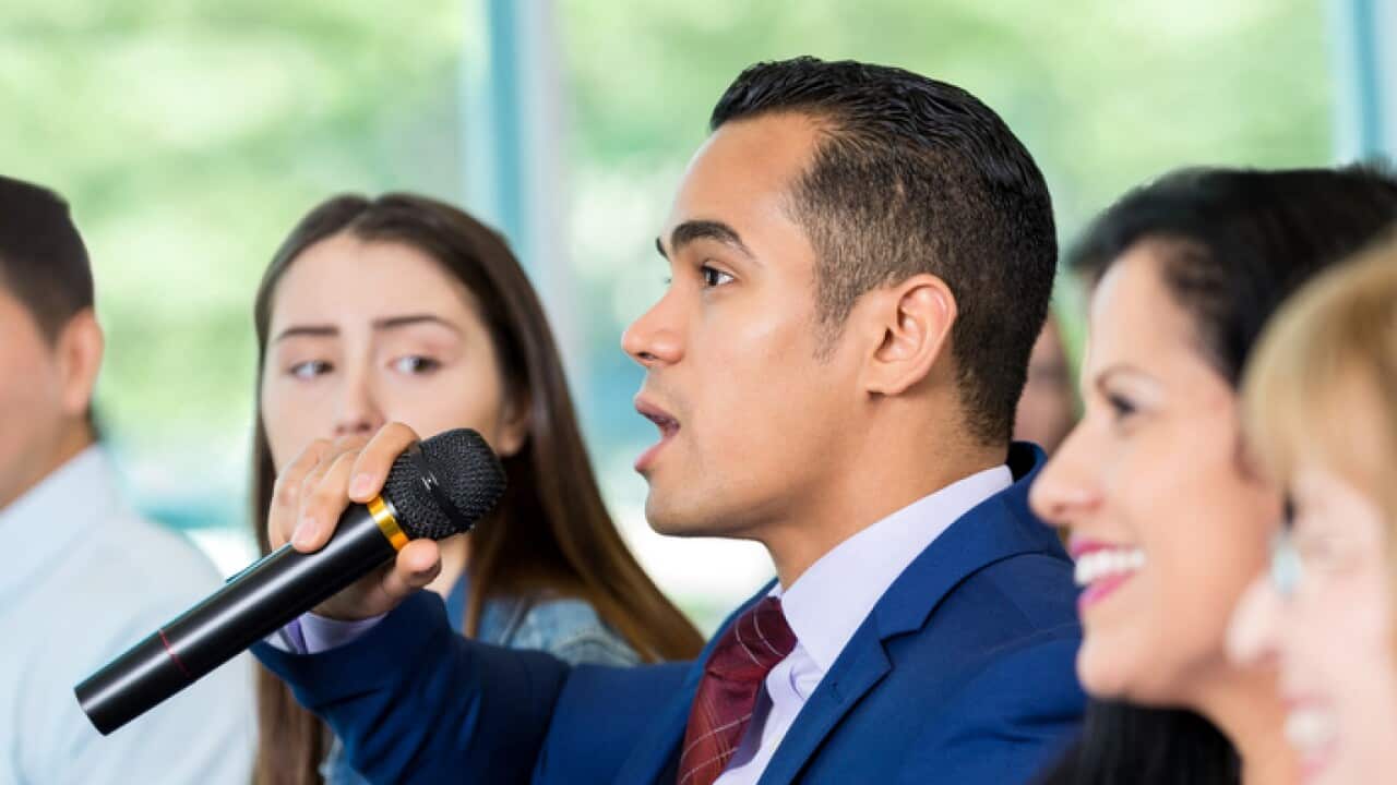 Concerned Hispanic citizen asks political candidate a question during meeting