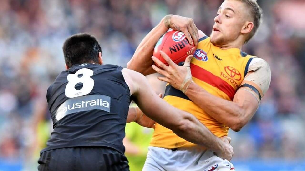 Hugh Greenwood of the Crows is tackled.