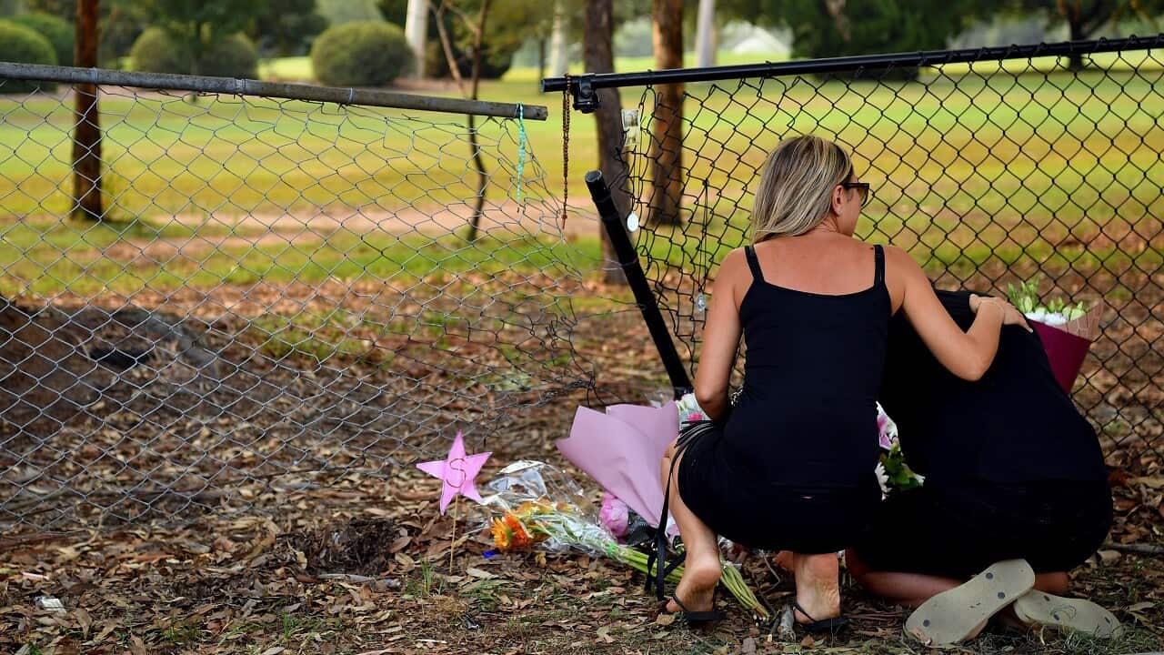 A man and woman near flowers placed at the scene where seven children where hit.