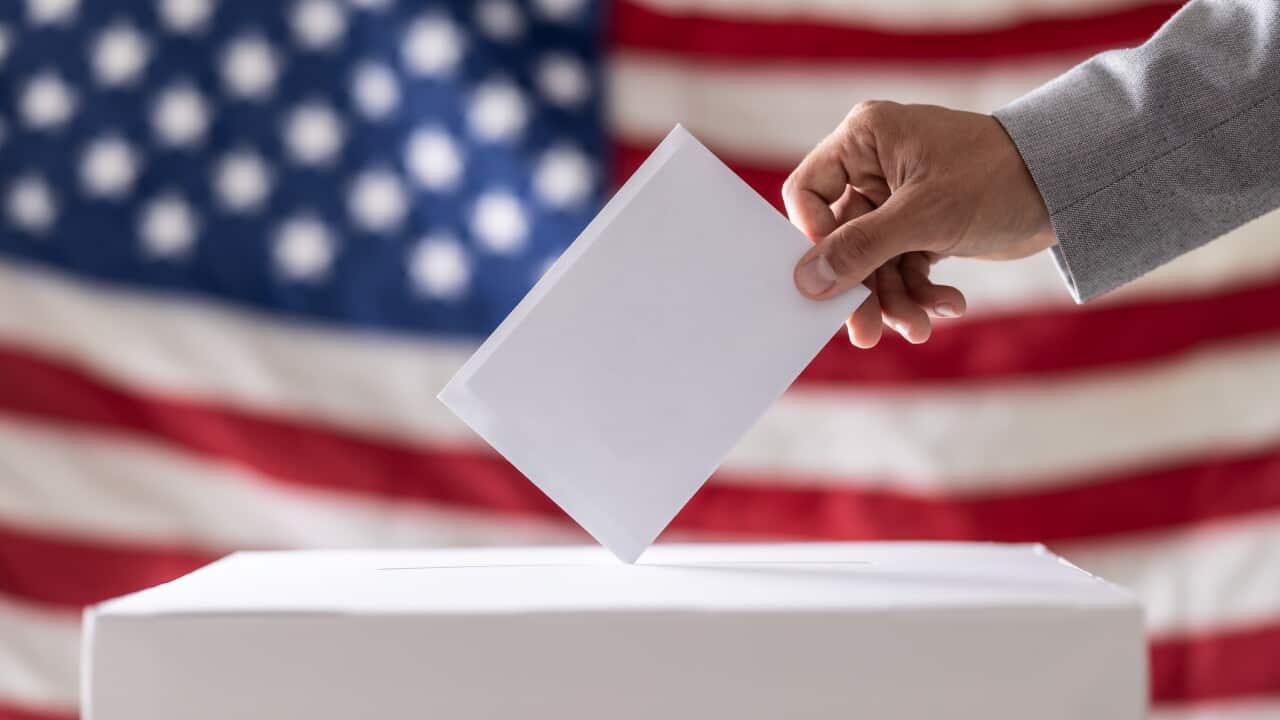 Election in USA. Man hand putting his vote into ballot box and American flag on background - Close up