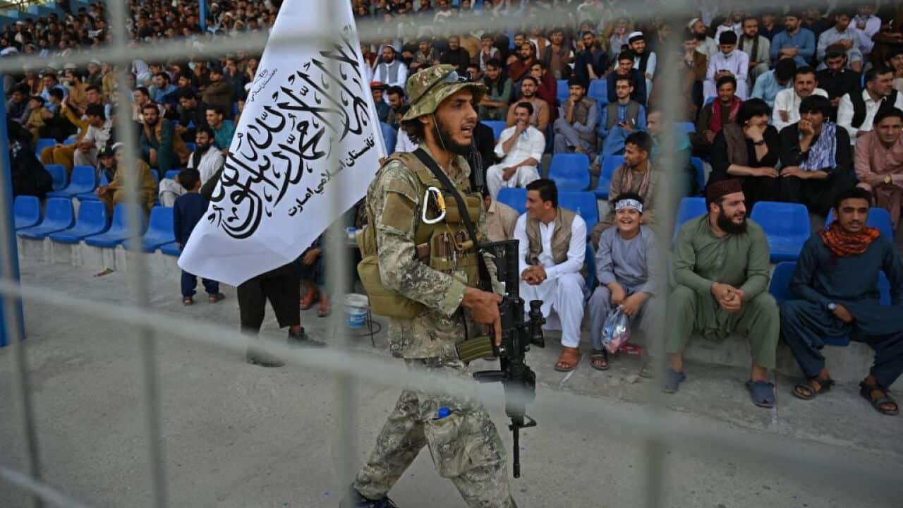 A Taliban fighter keeps vigil as spectators watch the Twenty20 cricket trial match being played between two Afghan teams in Kabul.