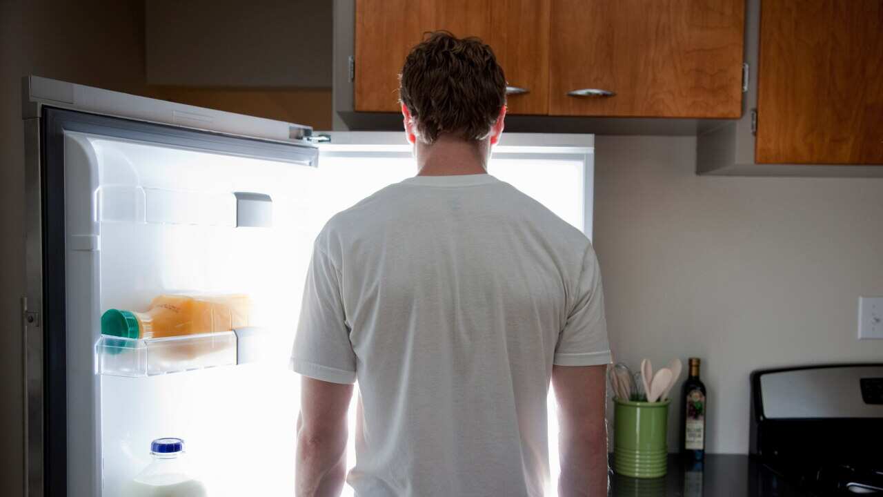 Man standing looking at contents of fridge