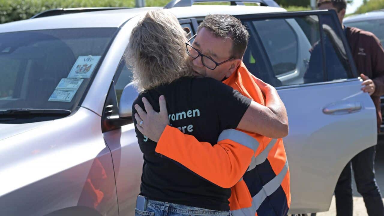 New Zealand Minister of Finance Grant Robertson (R) embraces Tukituki MP Anna Lorck during a visit to the Redclyffe power substation to inspect the flood damage and ongoing repair work.
