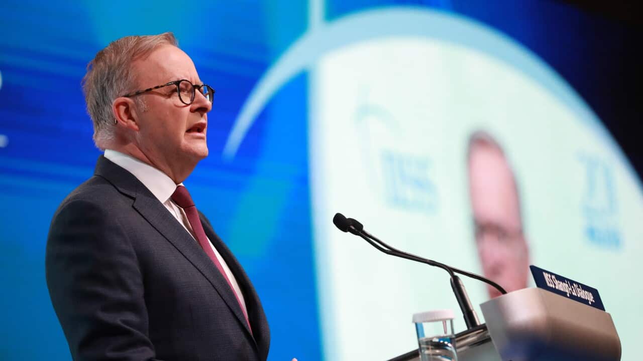 A man in a suit speaks with a mic in front of him