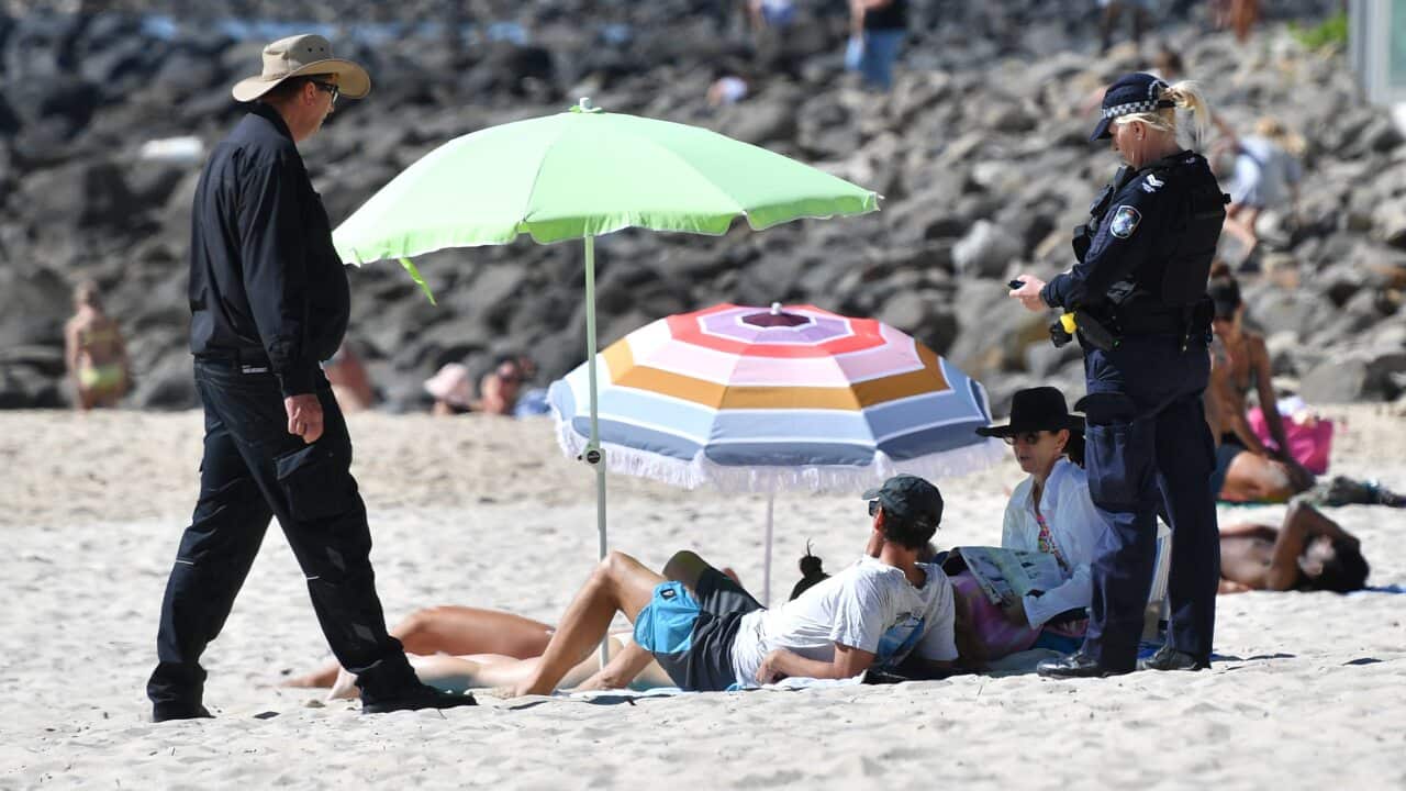 A police officer speaks to beachgoers at Burleigh Heads on Queensland's Gold Coast.