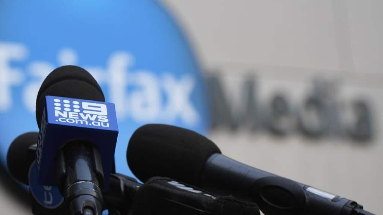 A Channel Nine microphone is seen against the signage of Fairfax Media