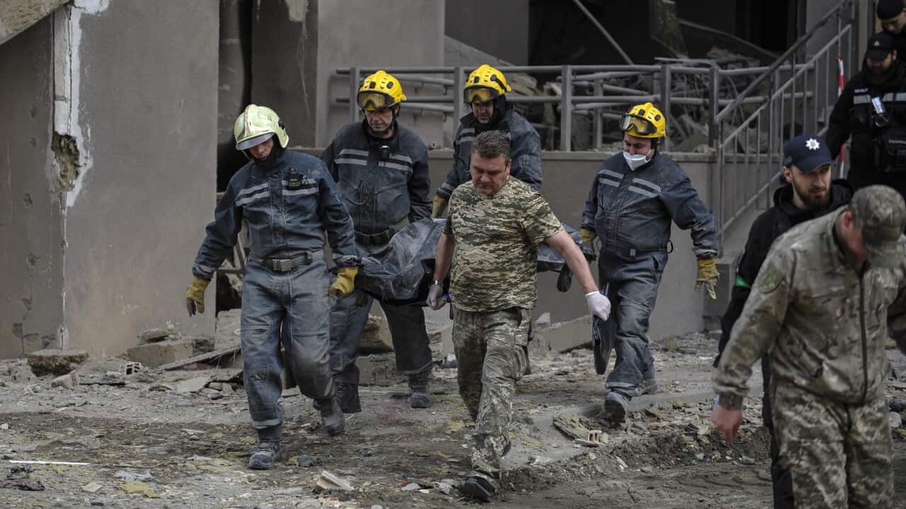 Rescuers carry the body of a dead woman who died during a