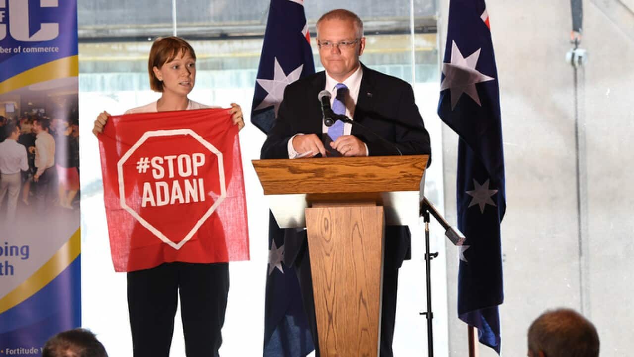 A Stop Adani protestor takes to the stage where Australian Prime Minister Scott Morrison was making a speech at the Valley Chamber of Commerce business luncheon in Brisbane, Monday, April 8, 2019. (AAP Image/Dave Hunt) NO ARCHIVING