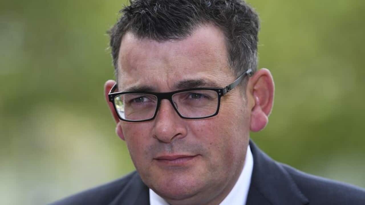 Victorian Premier Daniel Andrews looks on.