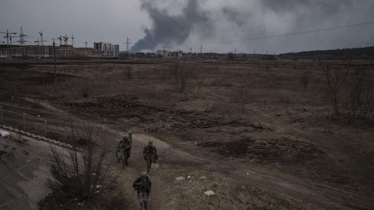 Soldiers walk on a path as smoke billows from the town of Irpin, on the outskirts of Kyiv, Ukraine, Saturday, 12 March, 2022.