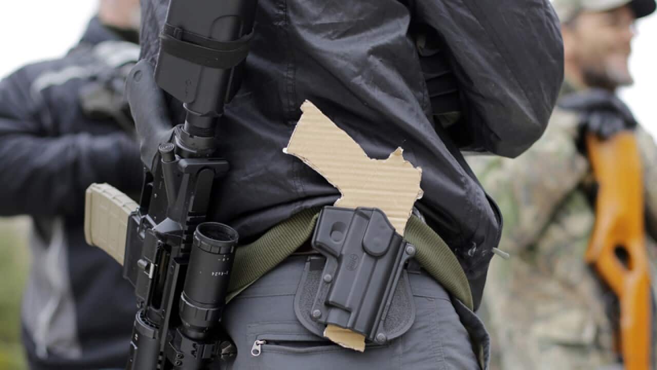 a gun-rights advocate carries a rifle and a cardboard pistol