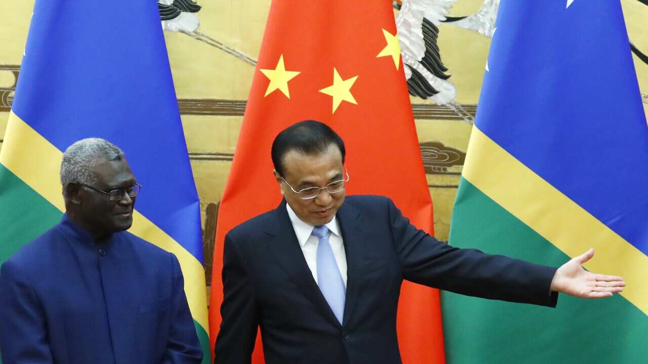 Solomon Islands Prime Minister Manasseh Sogavare, left, and Chinese Premier Li Keqiang stand in front of their country's flags.