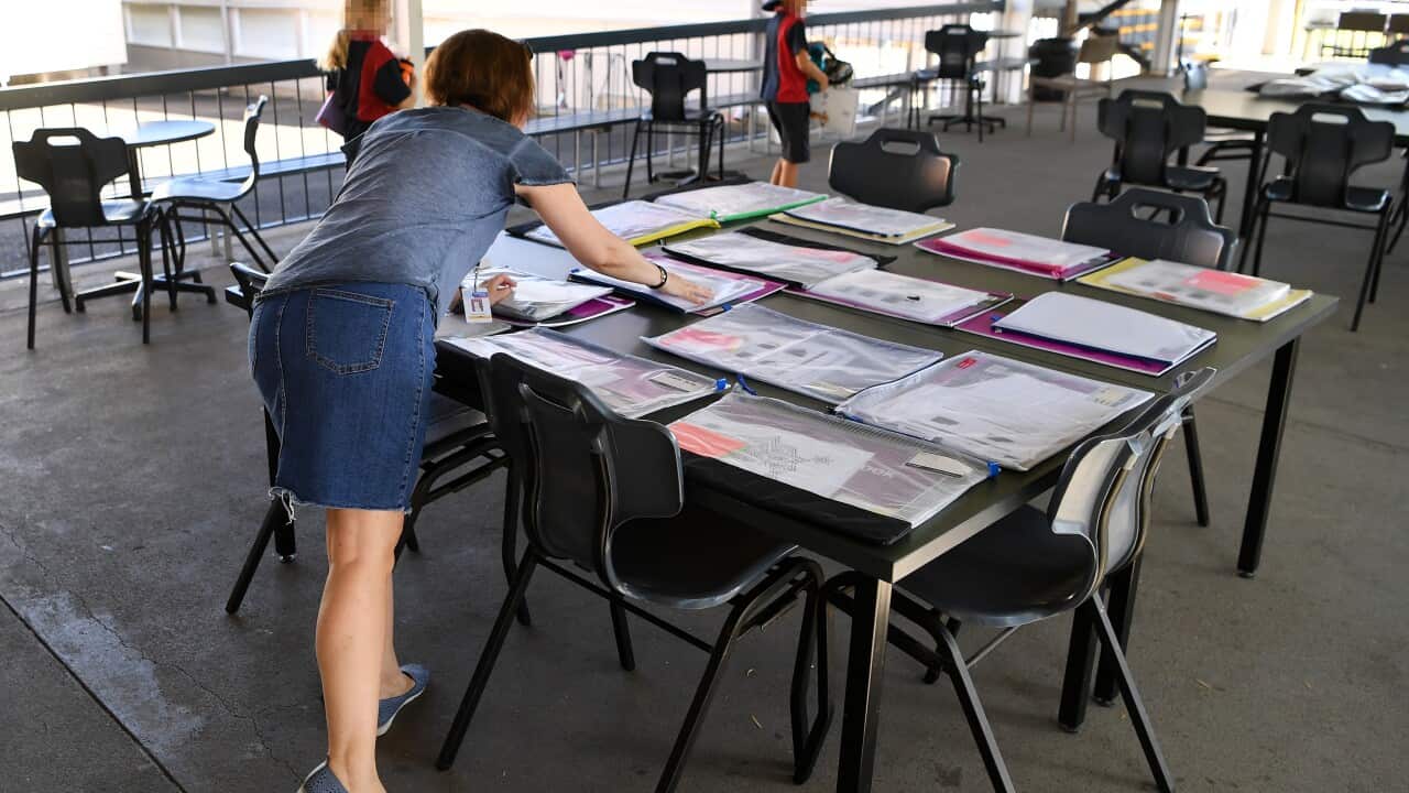 A teacher prepares a take-home activity packs at a primary school in Brisbane