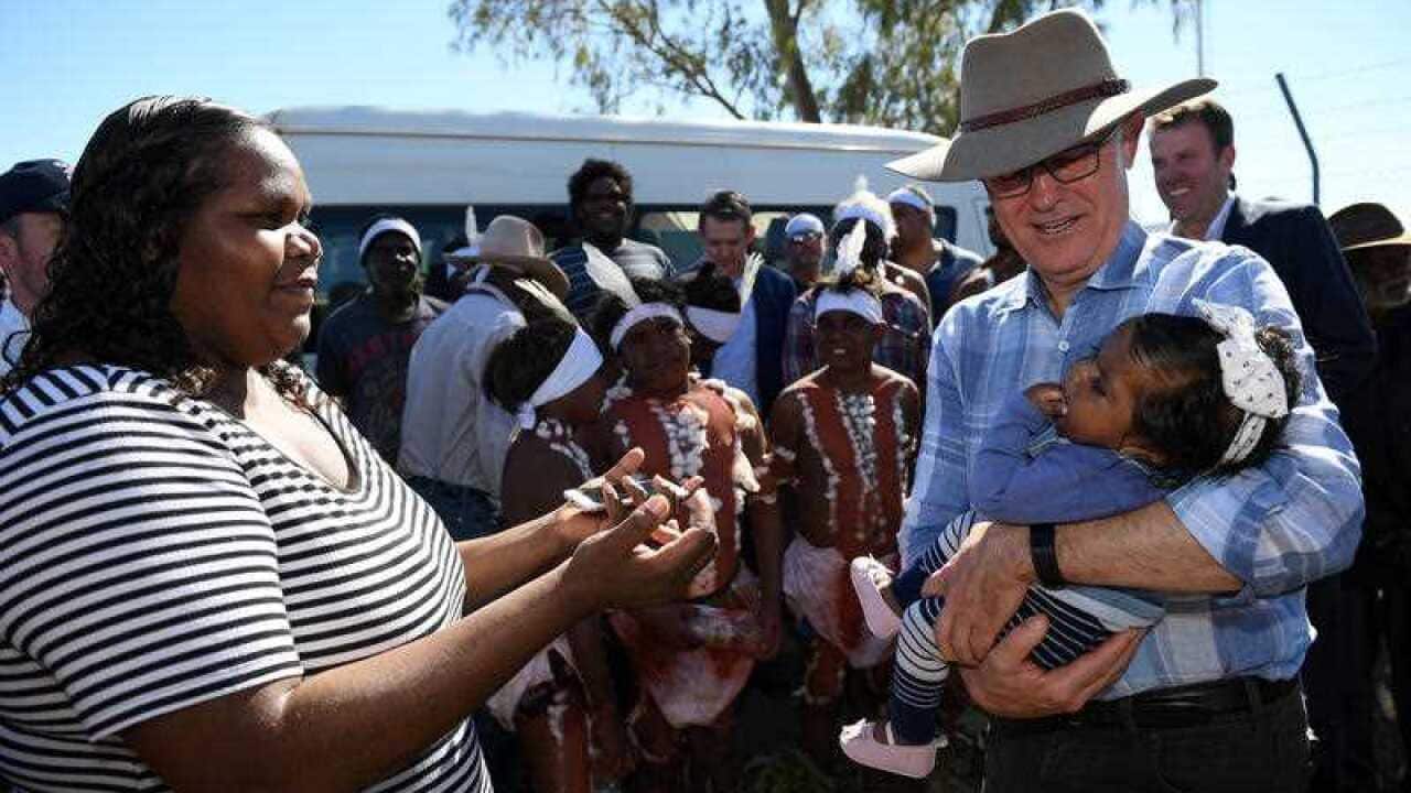 Prime Minister Malcolm Turnbull holds a baby as he arrives at Tennant Creek airport, in the Northern Territory, Sunday, July 22, 2018.