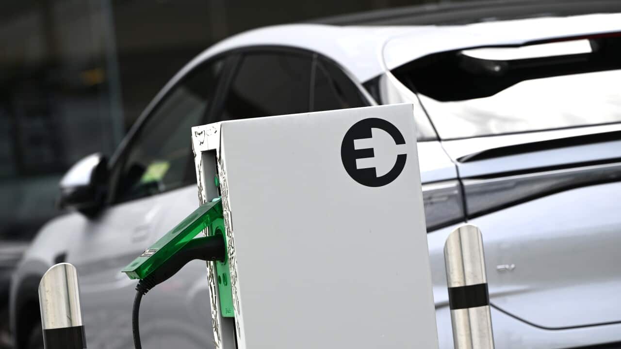 A white electric car is parked near a suburban charging station.
