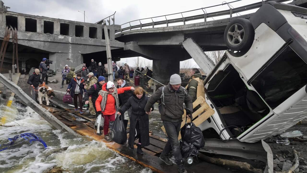 People cross an improvised path while fleeing the town of Irpin close to Kyiv