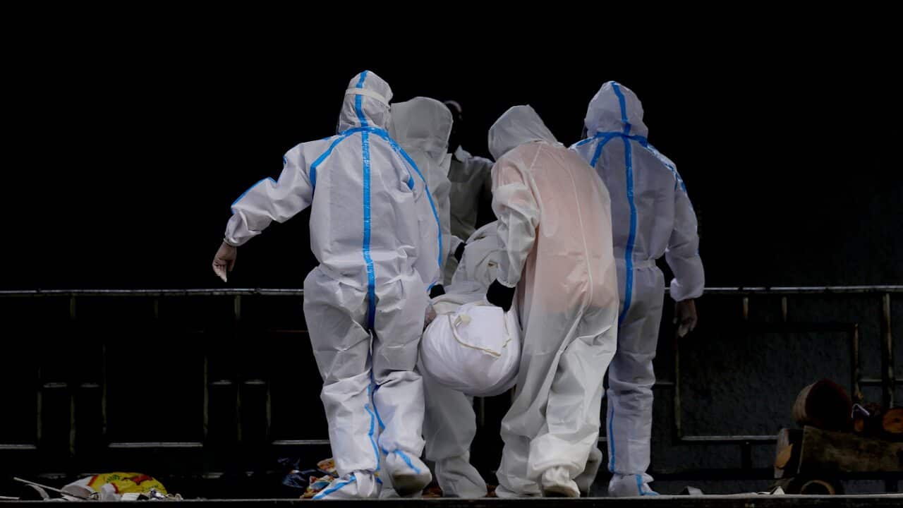 Relatives dressed in protective suits carry a body of their family member who died of coronavirus in India.