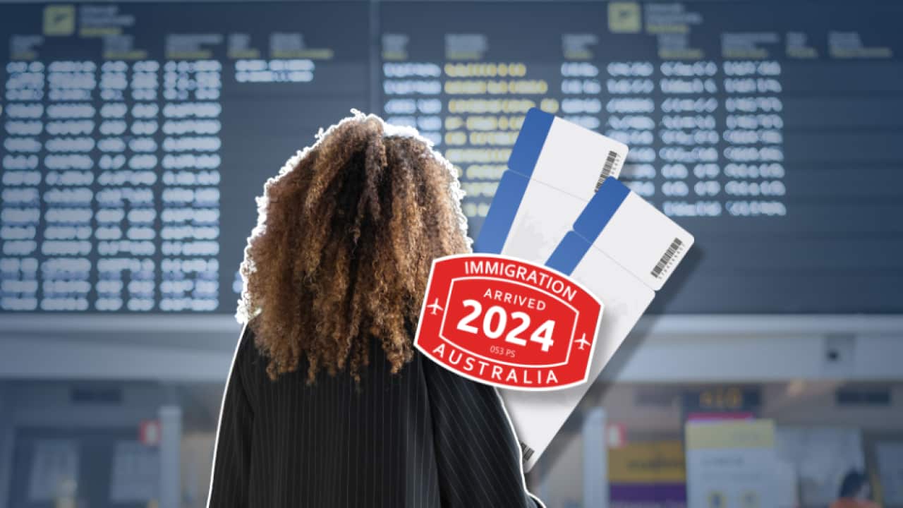 A woman with curly hair looks up at a airport display of flight times.