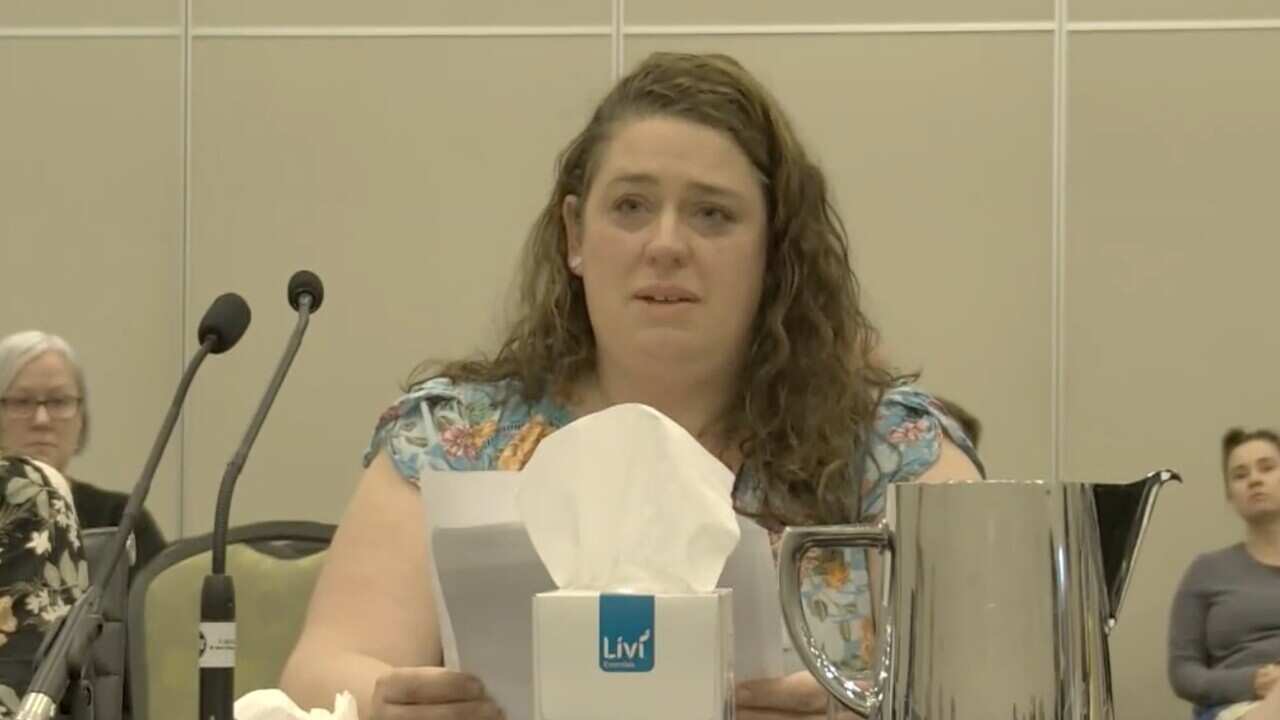 A woman cries as she speaks in front of a mic.