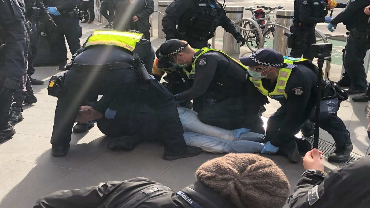 Police apprehend a man at an anti-vax protest outside Melbourne's Flinders Street Station.