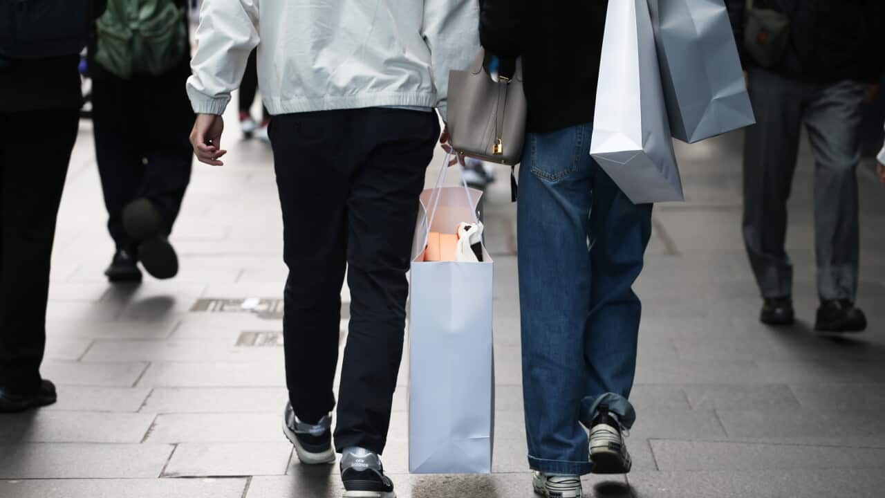 An image of shoppers' legs walking along a street holding bags