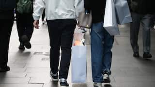 An image of shoppers' legs walking along a street holding bags