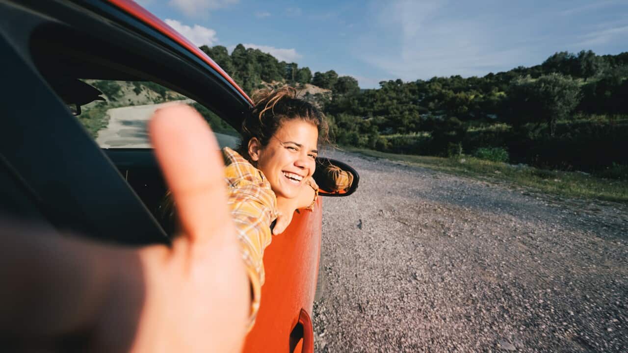 Woman video bloger traveling by electric car with a smart phone, recording video stories for social media