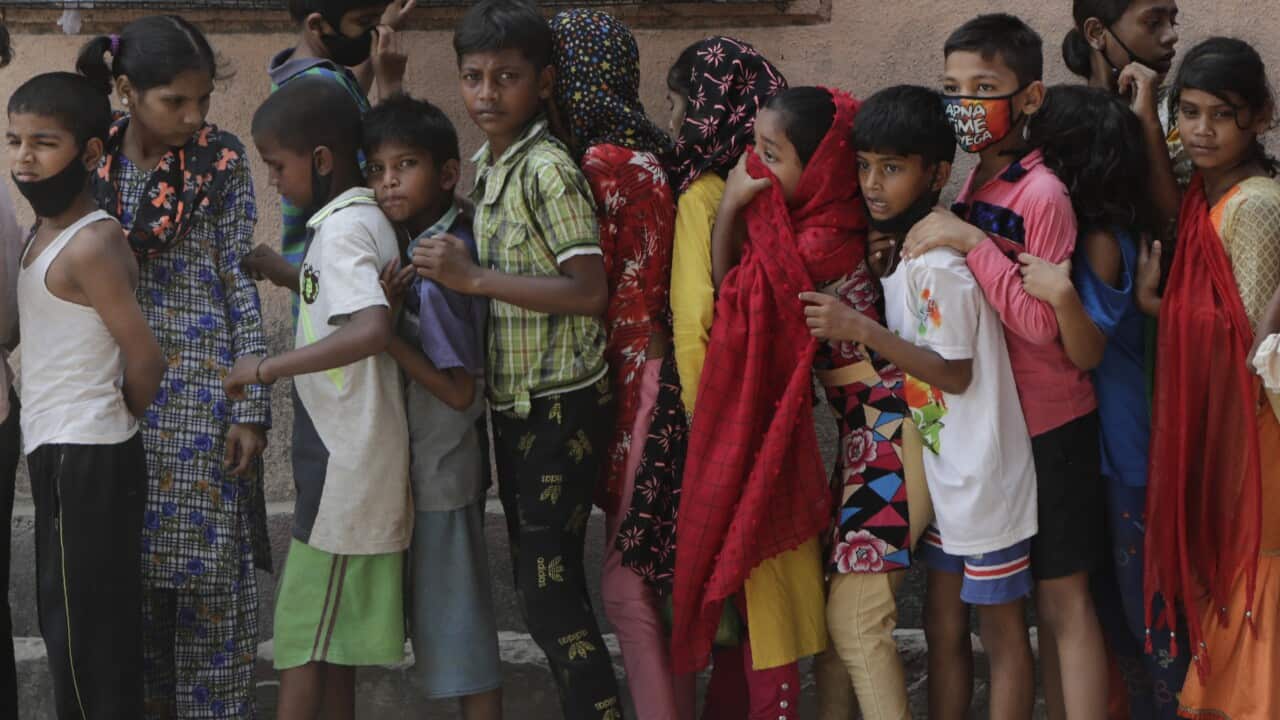 Children wait in a queue to receive food distributed in a slum during India's coronavirus lockdown.
