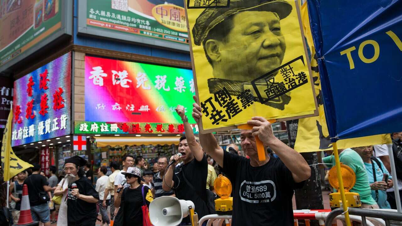 Protesters hold a poster of Chinese President Xi Jinping and shout slogans during the annual pro-democracy rally in Hong Kong.