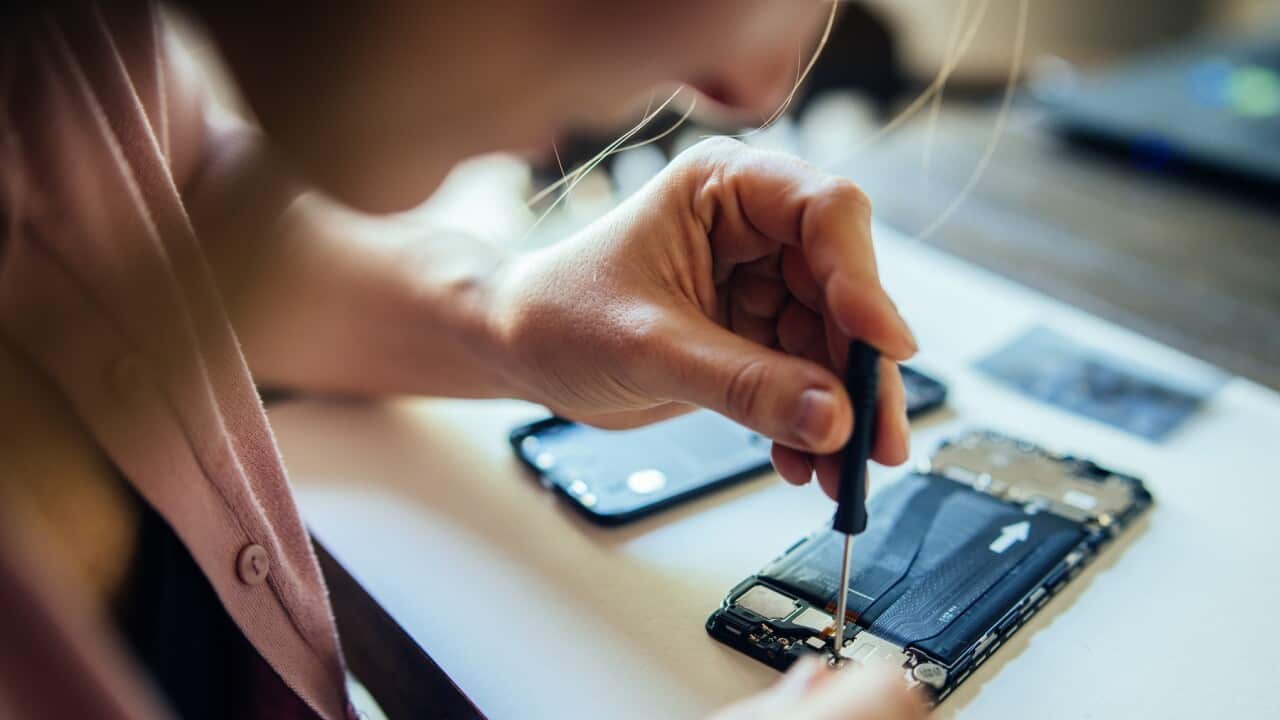 Woman repairing mobile phone at home, changing damaged part.