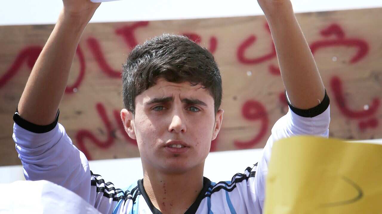 An Iraqi Yazidi holds up a sign saying "help our children and women" during a demonstration 