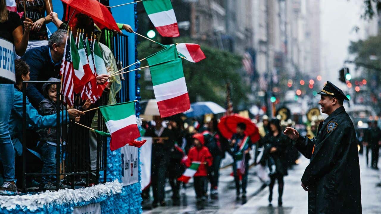 A police officer looks on as people with Italian flags march down Fifth Avenue during the Columbus Day Parade in New York.