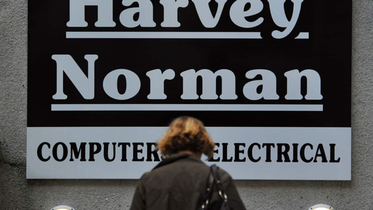 A consumer walks past Harvey Norman signage