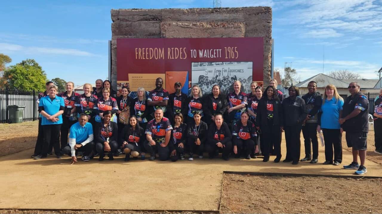 A group of people standing before a memorial which reads "Freedom ride to walgett 1965"